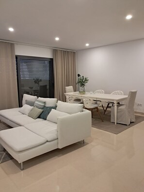 Ein modernes Wohnzimmer mit einem weißen Sofa, einem Esstisch und Stühlen.