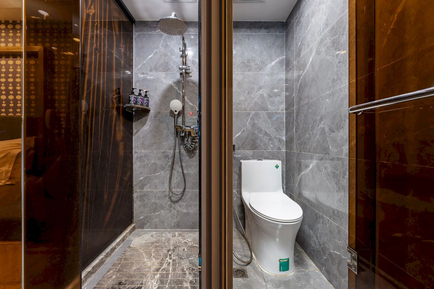 Ein modernes Badezimmer mit einer Glaskabine zur Dusche, einer weißen Toilette und Marmorwänden.