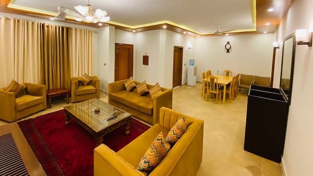 A living room with sofas, a coffee table, a dining area, and a ceiling fan.