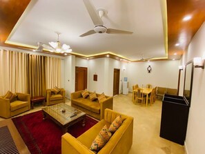 A living room with sofas, a coffee table, a dining area, and a ceiling fan.