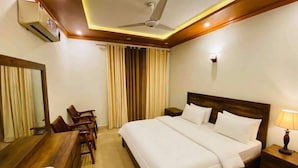A hotel room with a bed, bedside table, lamp, and a desk with chairs.