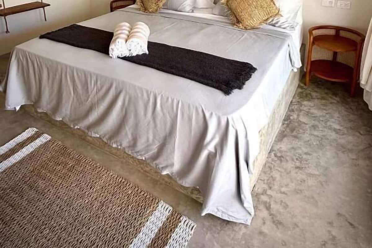 A neatly arranged bedroom with a large bed, hanging lights, and decorative wall art.