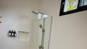 Ein Badezimmer mit Duschkabine aus Glas, einer weißen Toilette und einem Waschbecken mit blauen Handtüchern.