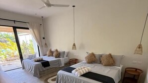 Ein Schlafzimmer mit zwei Betten, einem Holztisch und einem Deckenventilator.