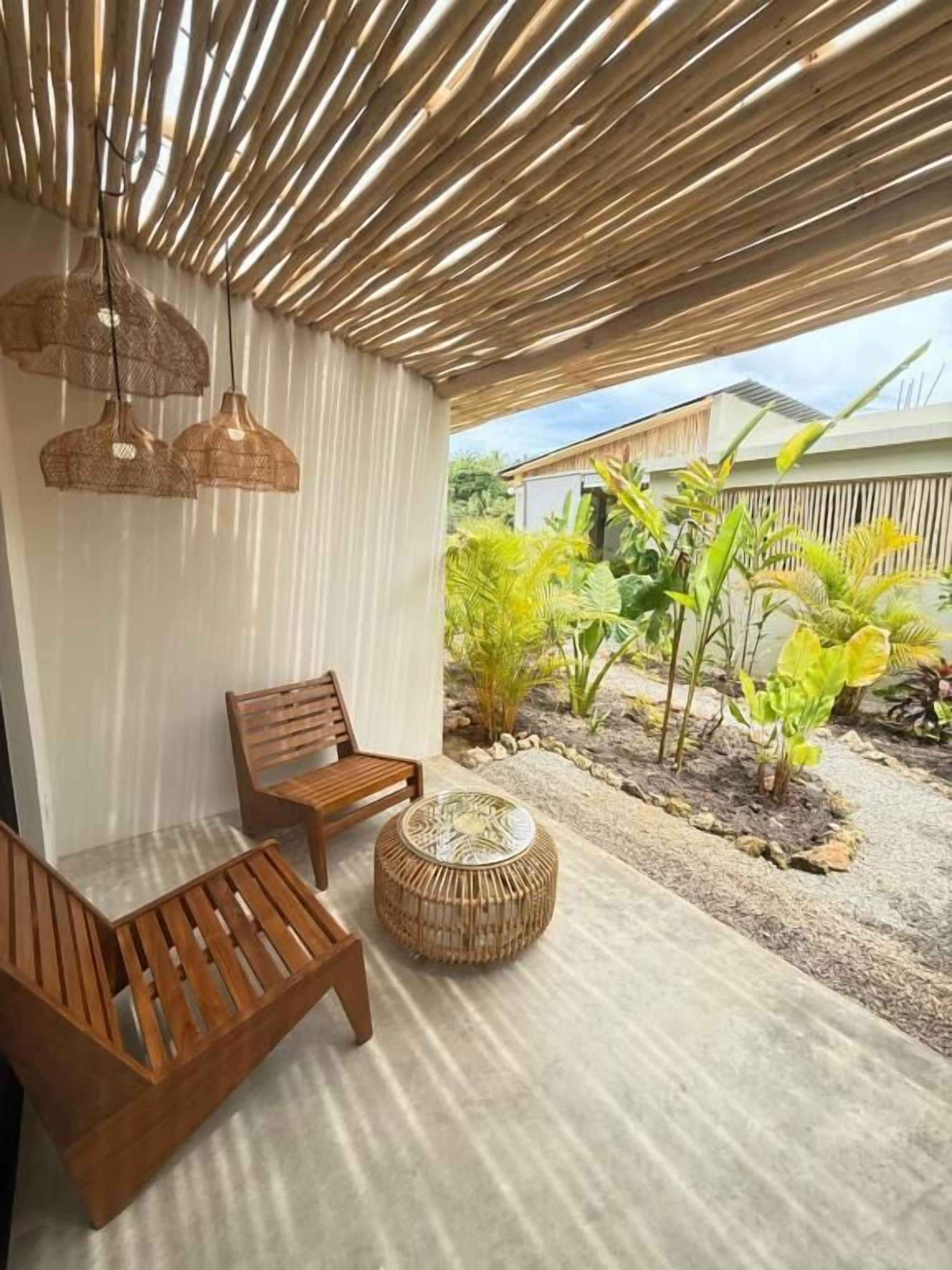 A covered outdoor seating area with wooden furniture and hanging lights.