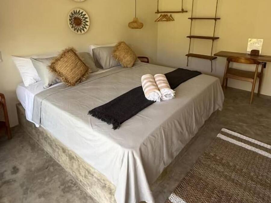 A bedroom with a bed, pillows, a bedside table, a desk, and wall decorations.
