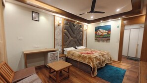 A bedroom with a bed, desk, chair, and a ceiling fan. - Cozy Wood Paneled Scenic Room with Walk-in Closet (Manali)