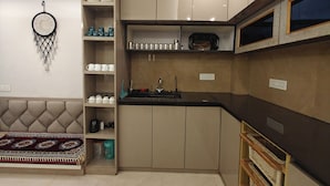 A compact kitchen with built-in cabinets, a countertop, and a dreamcatcher decoration. - Cozy Wood Paneled Scenic Room with Walk-in Closet (Manali)