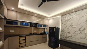 A modern kitchen with a black refrigerator, beige cabinets, and a marble backsplash. - Cozy Wood Paneled Scenic Room with Walk-in Closet (Manali)