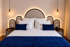 A hotel room with a large bed, two bedside tables, and a headboard with integrated lighting.