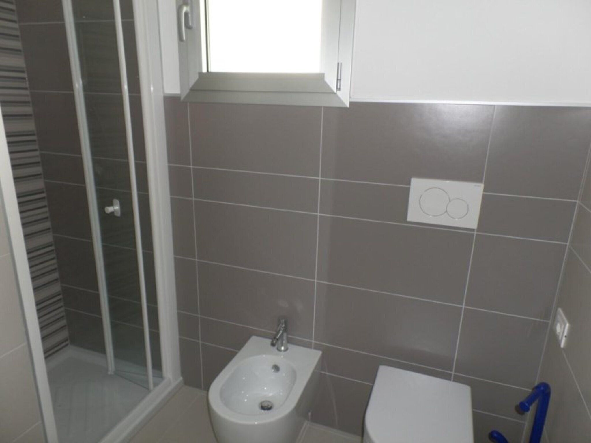A bathroom with a shower, bidet, and toilet.