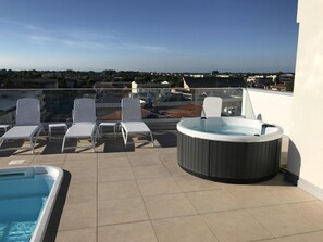 A rooftop terrace with a hot tub, lounge chairs, and a swimming pool. - Sleek Modern Home With a Rooftop Pool (San Michele al Tagliamento)