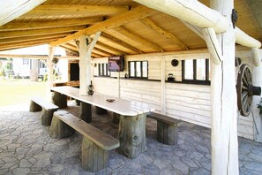 Una mesa de picnic de madera con bancos bajo una zona techada con suelo de piedra.