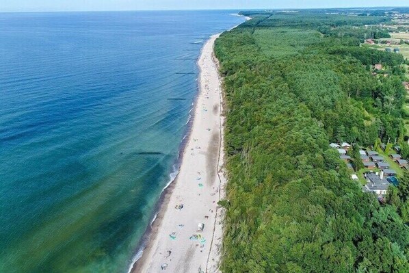 An aerial view of a beach with a forested area and buildings in the background. - Holiday homes, attractions for children (Rusinowo)