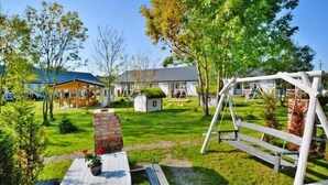 Een woonwijk met een houten terras, een bakstenen openhaard en een schommelset.