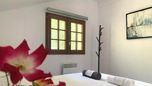 A hotel room with a bed, a window, a radiator, and a painting on the wall. - Small cottage in the woods with private pool (Saint-Jean-d'Estissac)