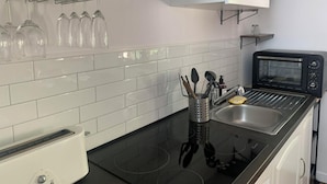 A modern kitchen with a black induction cooktop, a toaster oven, and a stainless steel sink. - Small cottage in the woods with private pool (Saint-Jean-d'Estissac)