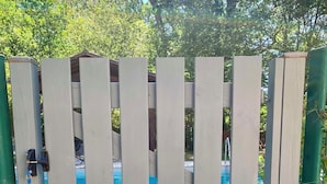 A gated area with a pool visible through the gate. - Small cottage in the woods with private pool (Saint-Jean-d'Estissac)