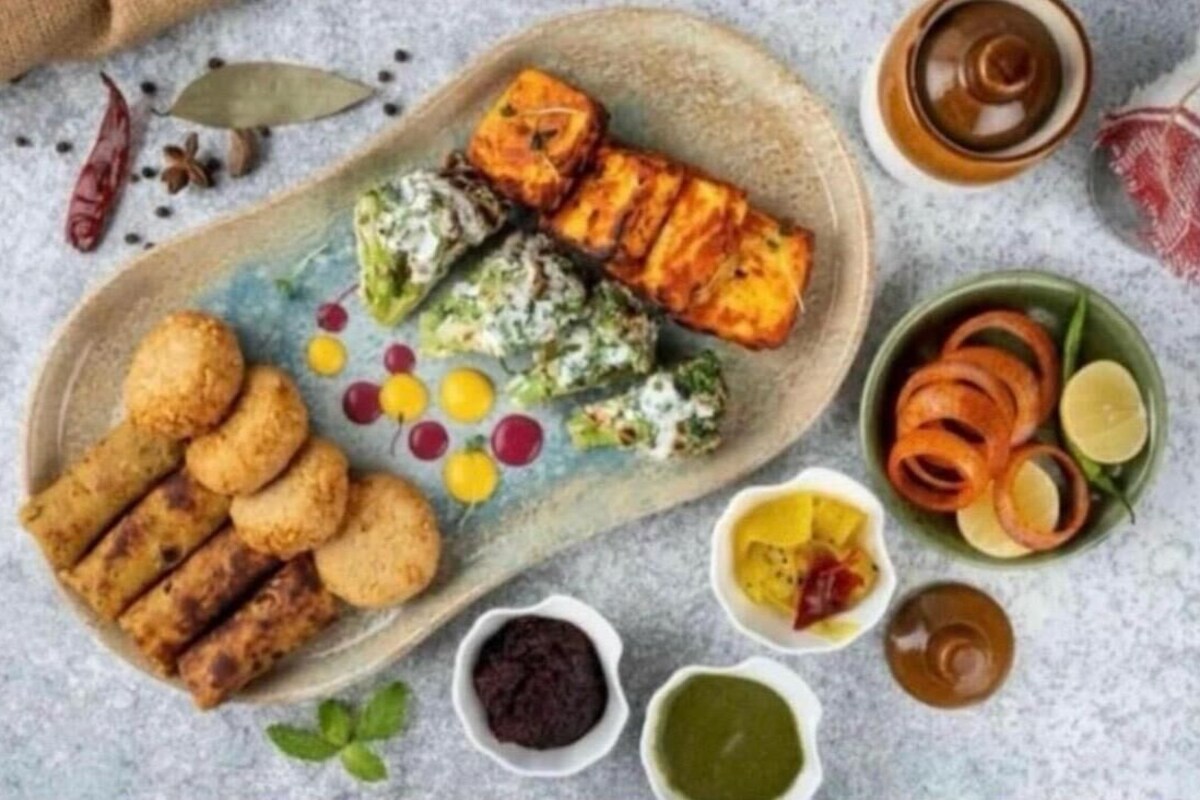 A plate with various food items including grilled meat, vegetables, and dips.