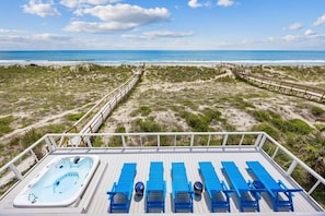 Una terrazza con idromassaggio e poltrone da relax blu che si affaccia su una spiaggia.
