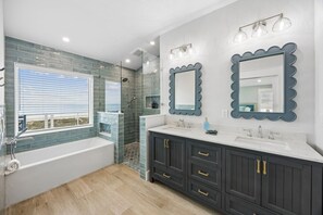 A modern bathroom with a bathtub, two sinks, dark cabinets, and a shower area. - Endless Summer | Brand New Oceanfront Beach House | Hot Tub | Elevator | EV Charger | Sleeps 17 (Fernandina Beach)