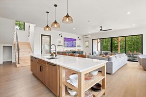A modern kitchen with a central island, wooden cabinets, and pendant lighting.