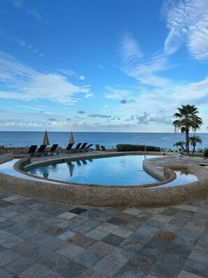 A pool with lounge chairs and a palm tree, surrounded by stone tiles. - Beautiful 2 BR. 2 bath, Sun & Sea Retreat, Rainbow Beach Club Sint Maartan .  (Cupecoy)