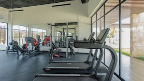 A modern gym with treadmills, weight machines, and a large window offering a view of the outdoors. - First floor, 4 pools, beach nearby, and gym (Punta Cana)