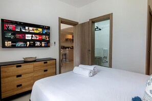 A hotel room with a bed, a TV displaying Netflix content, a wooden dresser, and a door leading to a bathroom. - First floor, 4 pools, beach nearby, and gym (Punta Cana)