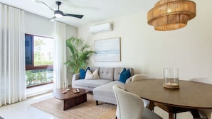 A modern living room with a sofa, coffee table, dining table, and chairs. - First floor, 4 pools, beach nearby, and gym (Punta Cana)