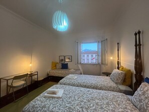 Ein Hotelzimmer mit zwei Betten, einem Schreibtisch, einem Stuhl, einem Fenster mit Blick und einer Hängelampe.