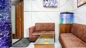 Une pièce comprenant un canapé, une table basse, un aquarium et un téléviseur fixé au mur.