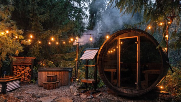 A rustic wooden structure with a large circular window, surrounded by a stone pathway and string lights. - Beautiful Farmhouse & thermal Spa in Forest (Sechelt)