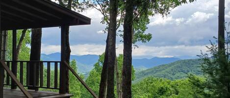 A wooden staircase leading to a covered area with a view of a forested mountain range.