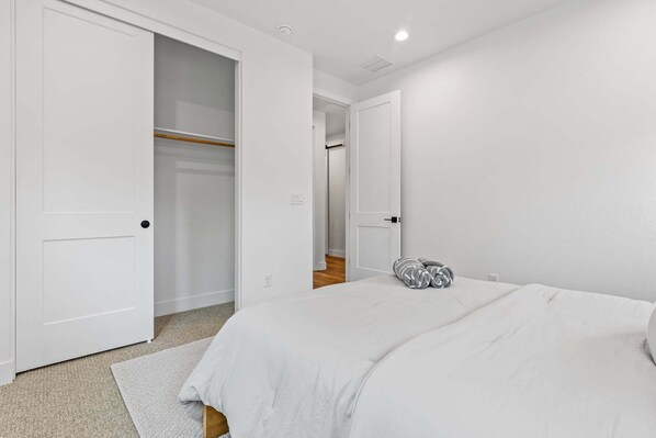 A bedroom with a bed, a closet, and a door leading to another room.
