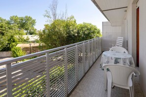 Ein Balkon mit weißem Geländer, einem Tisch mit Tischdecke und Stühlen.