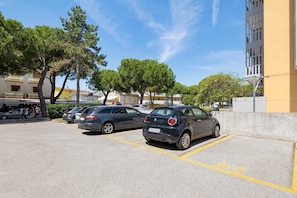 Ein Parkplatz mit Autos, Bäumen und Gebäuden im Hintergrund.