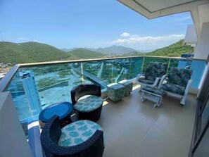 A balcony with a glass railing, outdoor seating, and a view of a mountainous landscape. - Spacious 3-bedroom apartment with AC in lovely Santa Marta (Santa Marta)