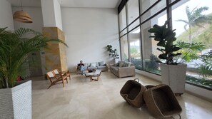 Eine geräumige Lobby mit einem großen Fenster, einer Steinsäule und mehreren Sitzbereichen.