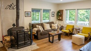 A living room with a fireplace, a sofa, a coffee table, and yellow chairs. - Serene Andes Retreat: A/C, BBQ & Nature (Andes)