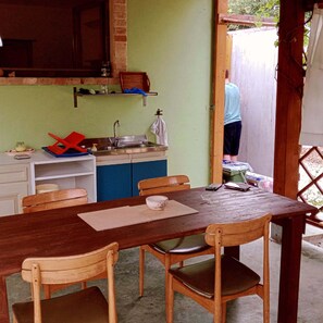 A kitchen with a sink, a wooden table with chairs, and a person standing by the door. - RIOMORO FARM (Abruzzo)