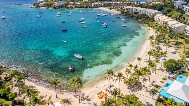 A coastal resort with clear turquoise waters, a sandy beach, and a row of villas. - Oceanfront steps to beach & yacht club-generator (St. Thomas)