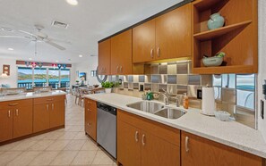 A modern kitchen with wooden cabinets, stainless steel appliances, and a view of the sea. - Oceanfront steps to beach & yacht club-generator (St. Thomas)