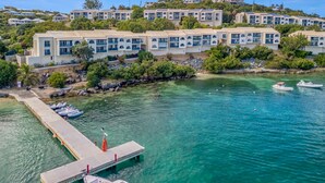 A coastal hotel with multiple-story buildings, a dock with boats, and clear turquoise water. - Oceanfront steps to beach & yacht club-generator (St. Thomas)