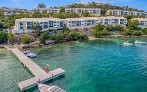 Un hotel costero con edificios de varios pisos, un muelle con barcos y agua turquesa cristalina.