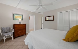 A bedroom with a bed, a chair, a dresser, a ceiling fan, and a wardrobe. - Oceanfront steps to beach & yacht club-generator (St. Thomas)