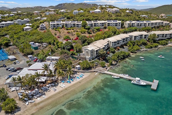 Um resort costeiro com edifícios de vários andares, uma praia e um cais com barcos.