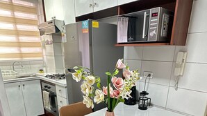 Una cocina moderna con alacenas blancas, un refrigerador de acero inoxidable, un microondas y una estufa a gas.