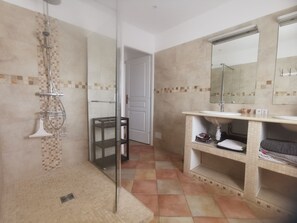 A bathroom with a shower, a sink, a mirror, and a tiled floor. - Spacious apartment near Lake Sainte-Croix, surrounded by truffle oaks. (Sainte-Croix-du-Verdon)