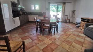 A kitchen with a dining table and chairs, a built-in oven, and a view of the outdoors. - Spacious apartment near Lake Sainte-Croix, surrounded by truffle oaks. (Sainte-Croix-du-Verdon)